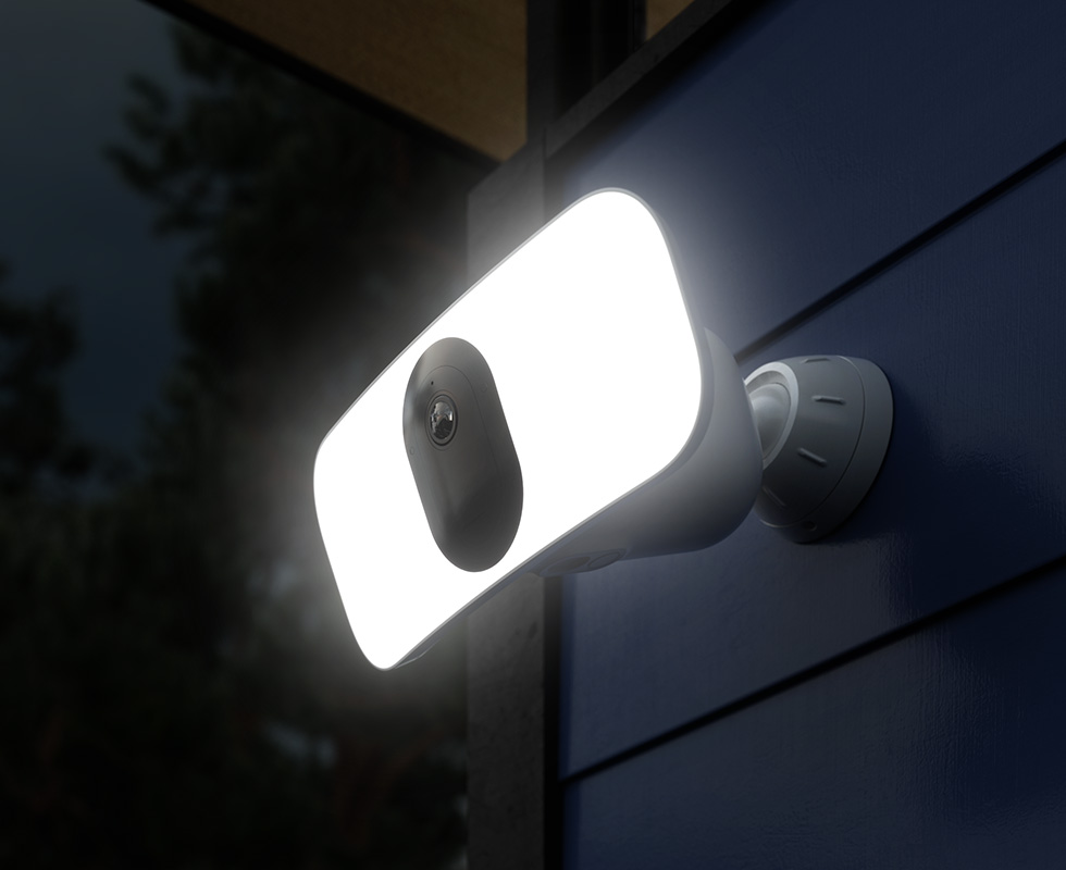 Arlo Pro 3 Floodlight security camera shining bright at night attached to a house