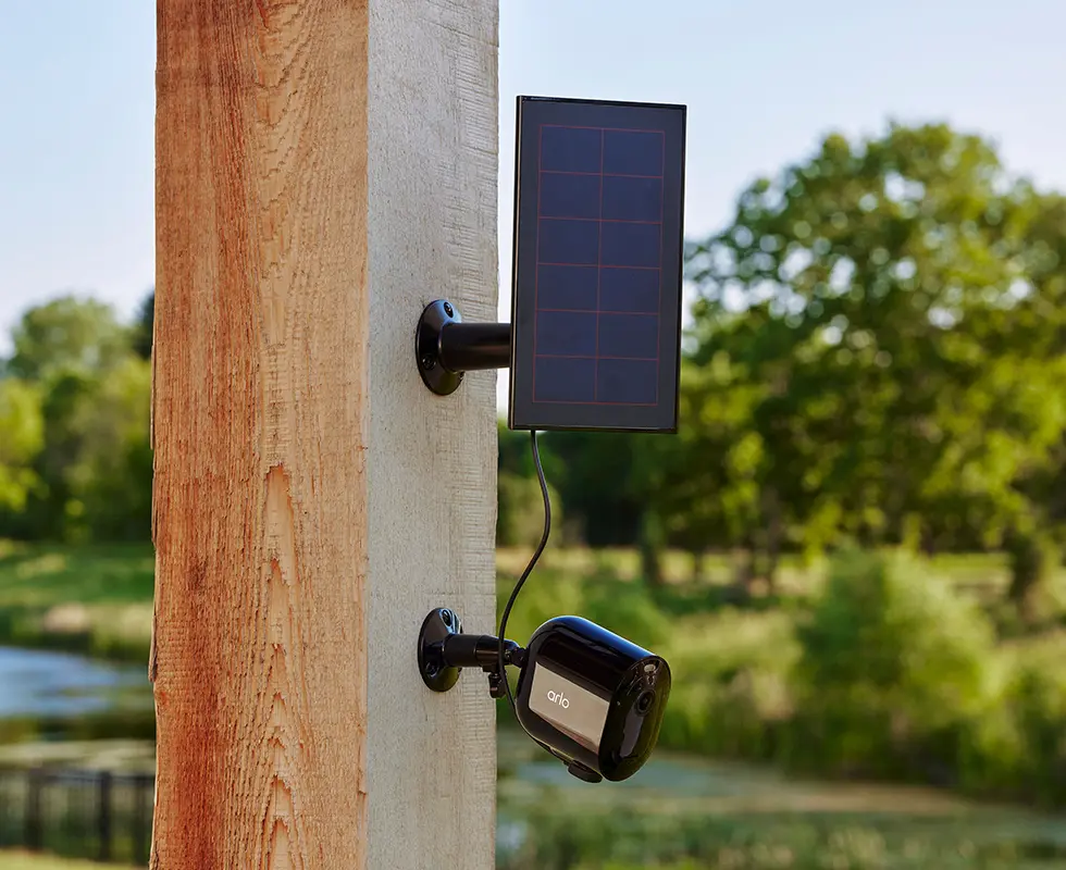 Arlo Go 2 wireless security camera with a solar panel charger outdoors attached to a wooden post