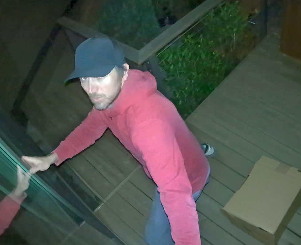 Package thief caught on an apartment porch in night vision on an Arlo Essential wireless security camera