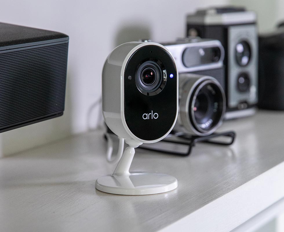 Arlo essential indoor security camera blending-in next to other electronics inside a house