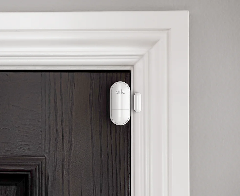 Arlo all-in-one sensor attached to the top corner of a door